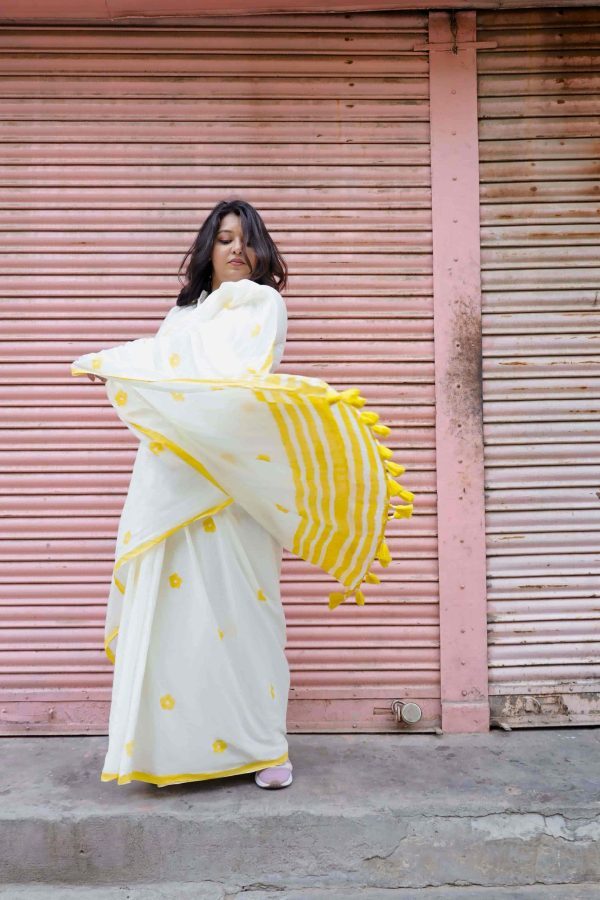 Bahara cotton saree in white with yellow daisy motifs, yellow striped border and pallu, tassels, and matching blouse fabric.