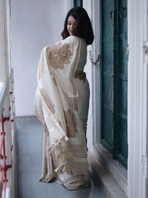 Komal cotton saree in almond beige with hand-block printed brown floral motifs, dark brown border, tassels on the pallu, and matching blouse piece.