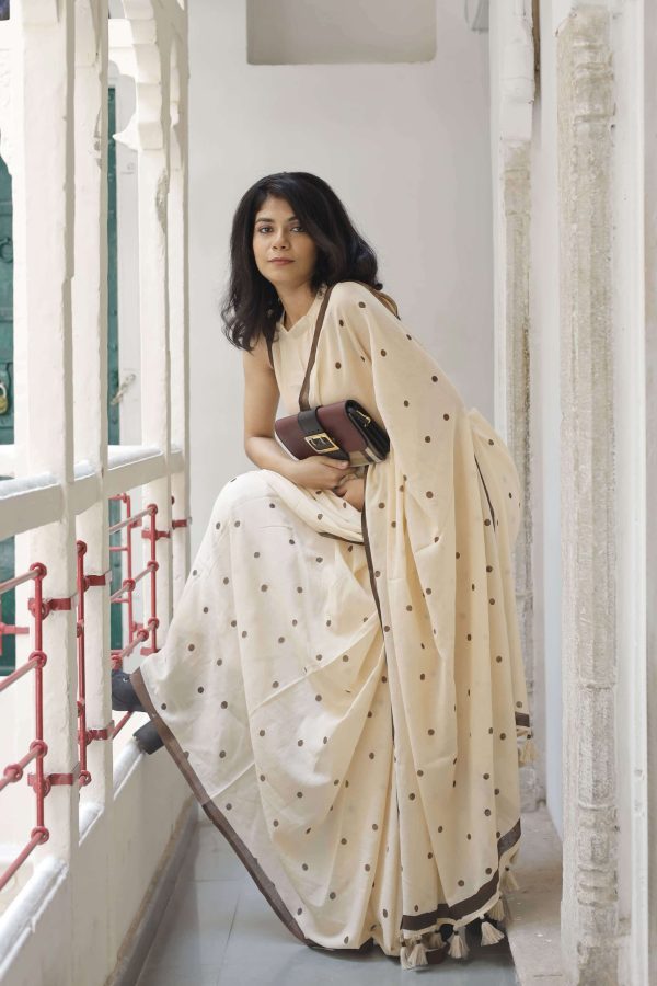 Melody Dots cotton saree in oat beige with hand-block printed dark brown polka dots, dark brown border, tassels on the pallu, and matching blouse fabric.