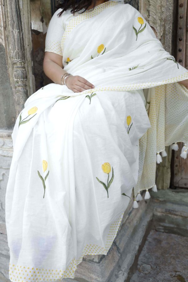 Resham Si Baat saree in soft off-white cotton with yellow tulip motifs, dotted yellow and green border, tassels, and matching blouse fabric.