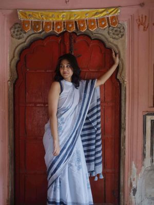 Saawan saree in cloudy blue cotton with dark and light indigo floral motifs, striped pallu, and tassels, styled with matching blouse.