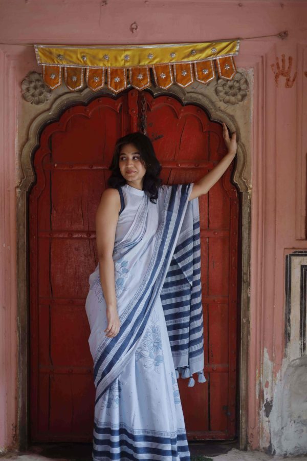 Saawan saree in cloudy blue cotton with dark and light indigo floral motifs, striped pallu, and tassels, styled with matching blouse.
