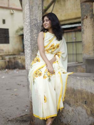 Suraj Mukhi cotton saree in buttermilk yellow with sunflower bouquets, yellow striped border, tassels with yellow beads, and matching blouse fabric.