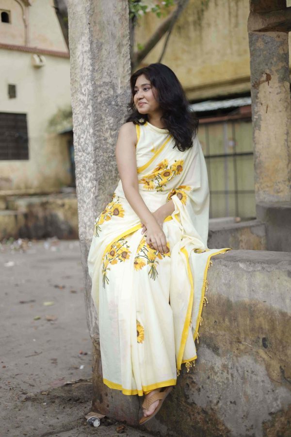 Suraj Mukhi cotton saree in buttermilk yellow with sunflower bouquets, yellow striped border, tassels with yellow beads, and matching blouse fabric.