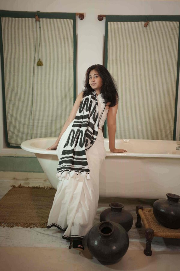 Aakhiri Panna white cotton saree with black abstract block-printed pallu, bold black border, tassels, and matching blouse piece.
