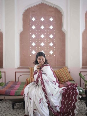Aamchi saree in chalk white cotton with black mango motifs made of florals, maroon stem and leaf, bold maroon wave border, tassels, and matching blouse piece.