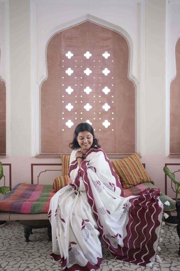 Aamchi saree in chalk white cotton with black mango motifs made of florals, maroon stem and leaf, bold maroon wave border, tassels, and matching blouse piece.