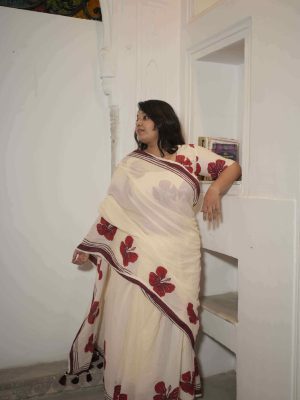 Surmayi cotton saree in cream with red hibiscus motifs along the hem, maroon striped border, tassels, and matching hibiscus print blouse fabric.